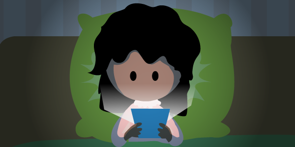 Niña por la noche en su habitación haciendo uso de su dispositivo móvil a oscuras